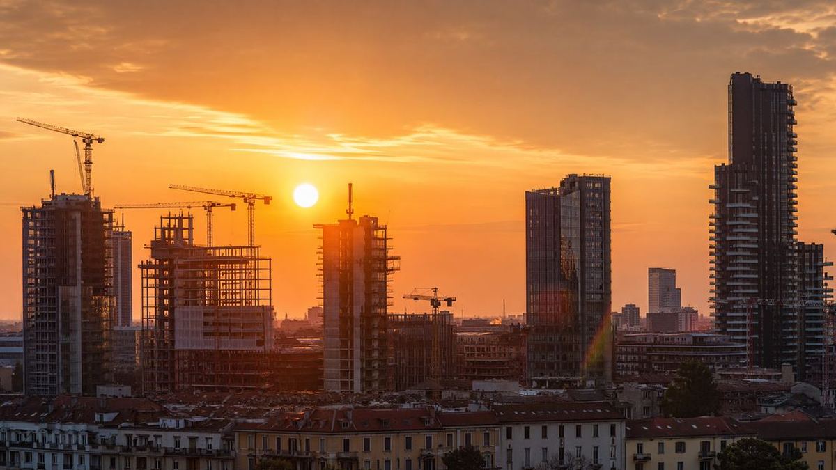 Skyline residenziale di Milano al tramonto con gru edili