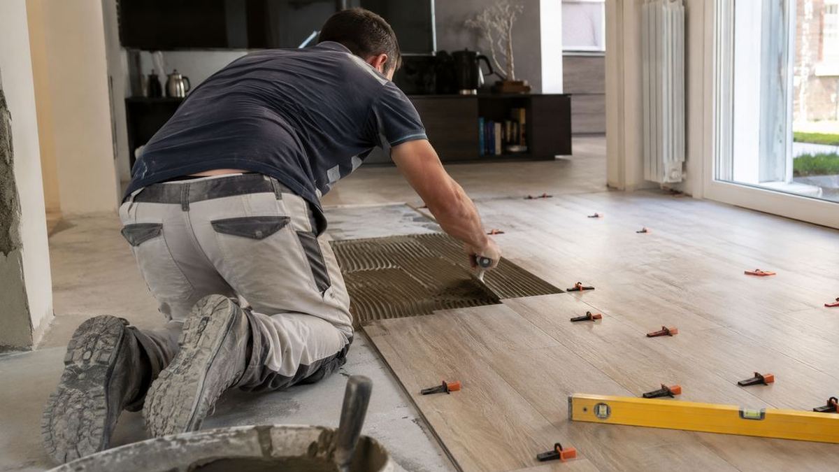 Posatore installa pavimento in gres effetto legno in un soggiorno moderno